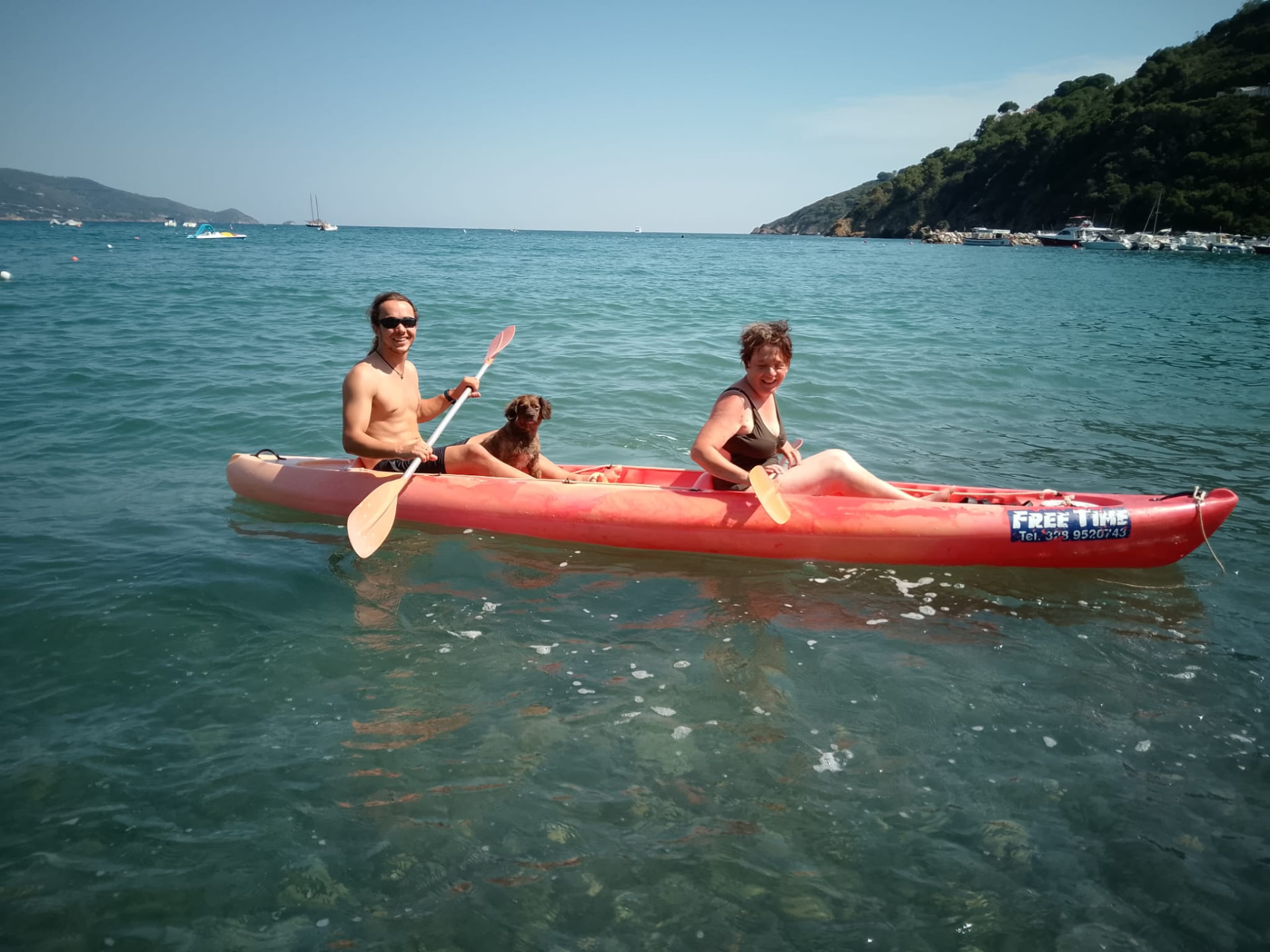 Canoa rossa con ospiti e cane nelle acque cristalline di Margidore